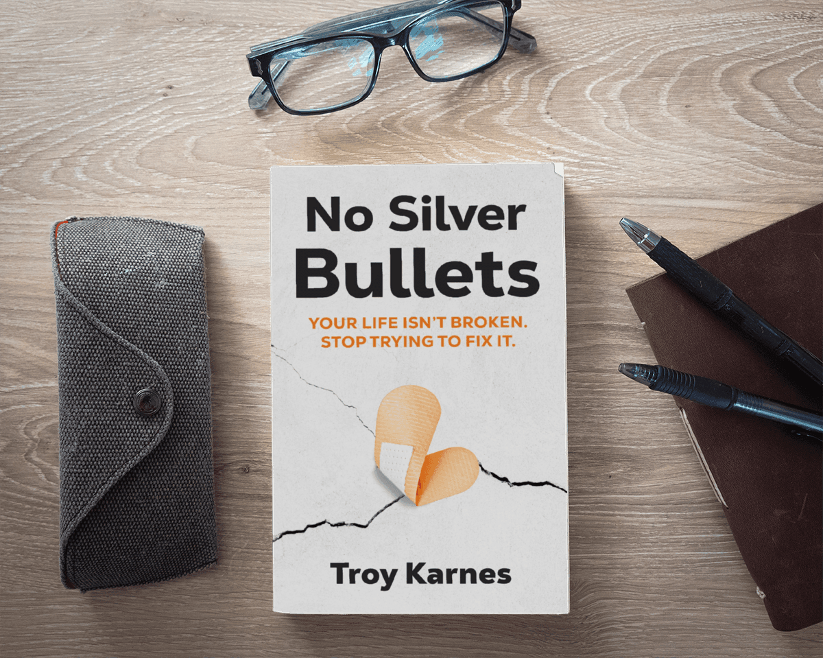 No Silver Bullets by Troy Karnes, book cover on a desk with reading glasses and a notebook